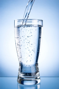 Pouring water into glasson on a blue background